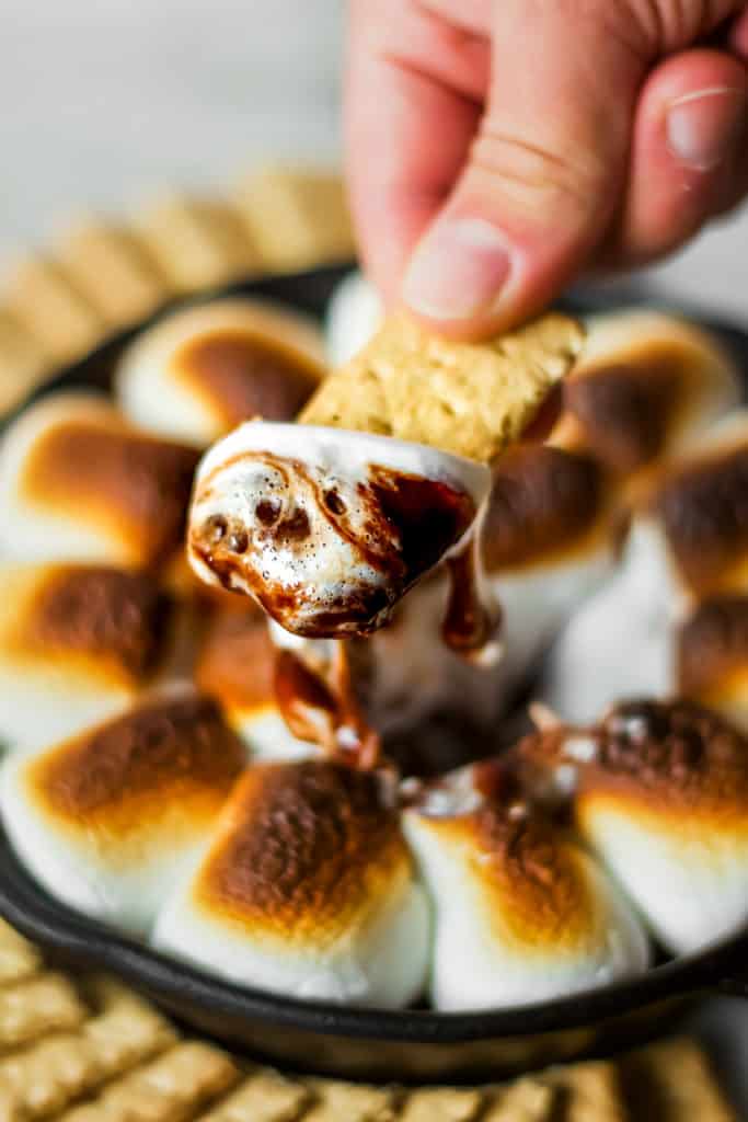 s'mores fondue with chocolate and marshmallows dripping off of a graham cracker