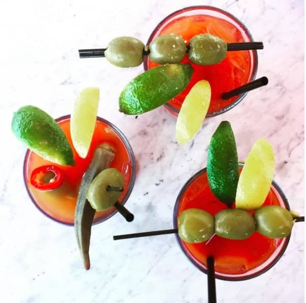 three bloody mary cocktails on a white table top made with a diy bloody mary bar