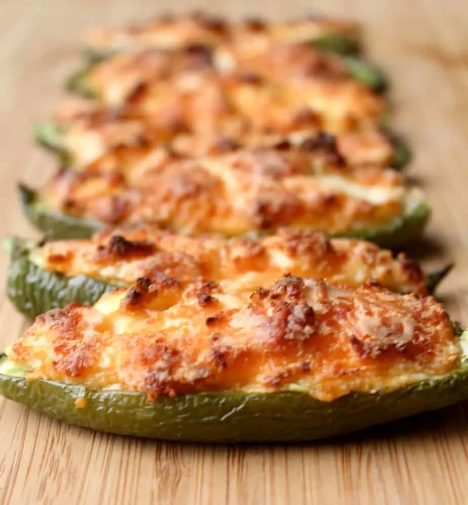 jalapeno pepper is cut in half and then stuffed with cheese, baked and served on a wooden board.