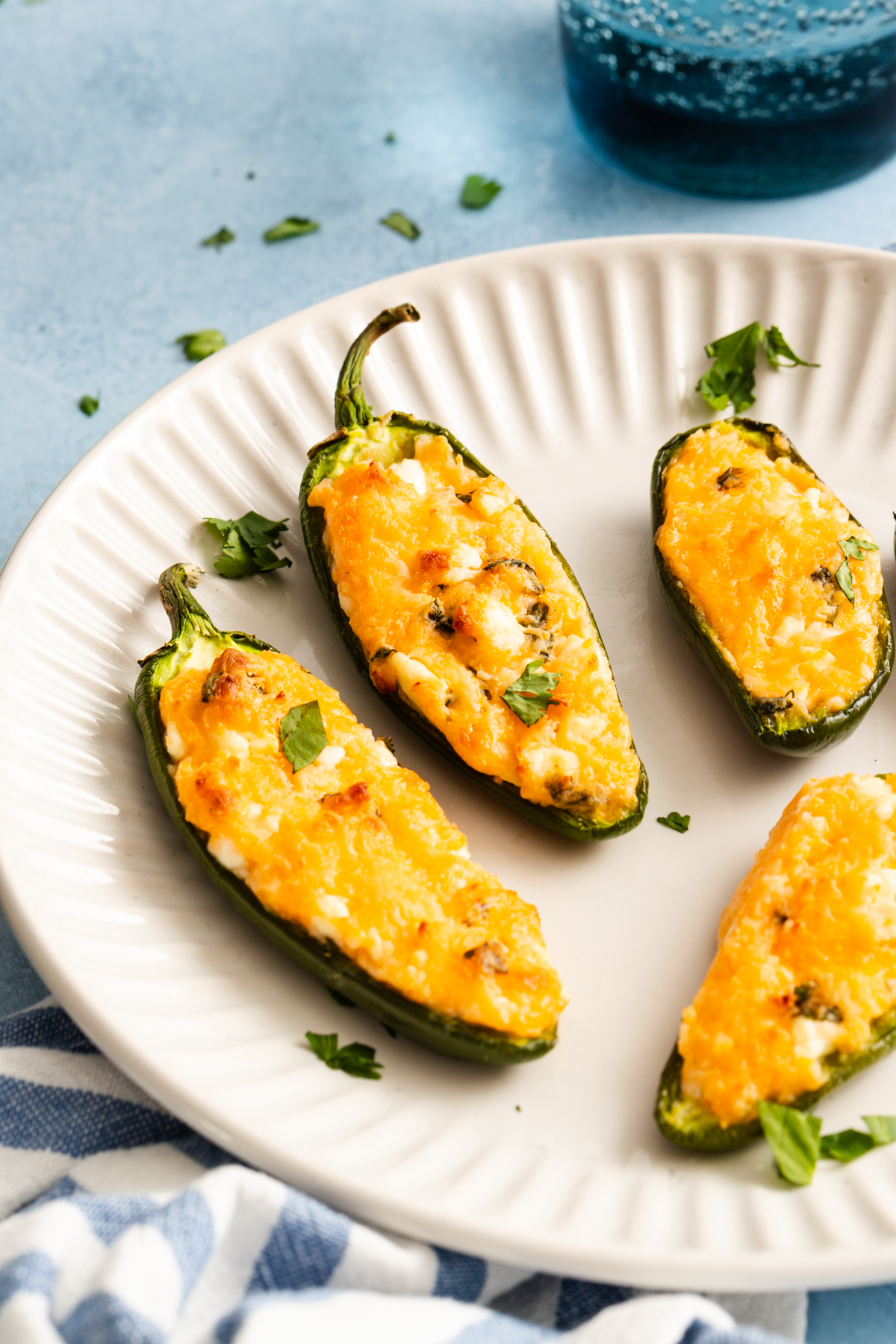 Four jalapeño poppers filled with melted cheese on a white plate.