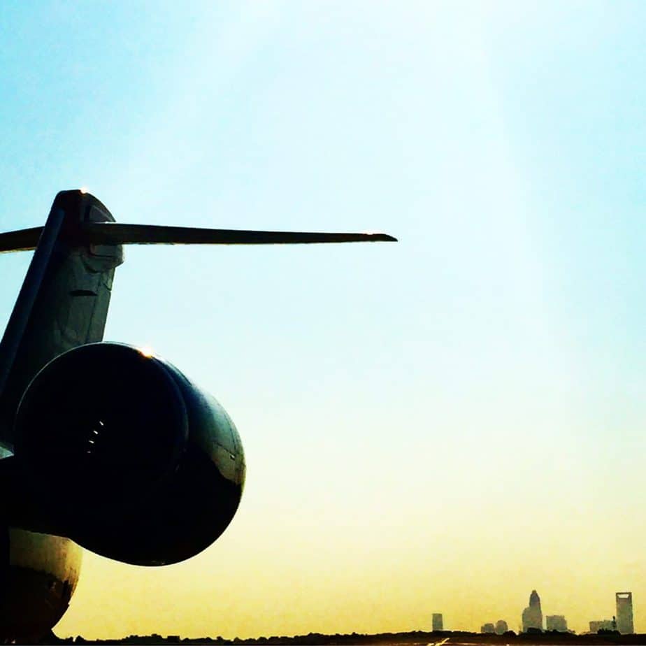 The tail and engine of an airplane are visible on the left side, set against a bright blue sky with a distant city skyline—an inspiring view perfect for marking a special blogiversary.