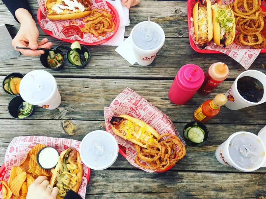 eating hot dogs in red baskets with condiments at a picnic table at jj's red hots