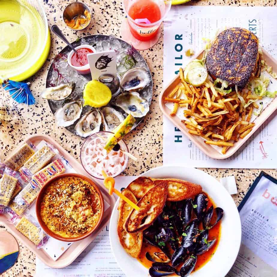 mussels, burger, oysers and cocktails on a table with hello sailor menus