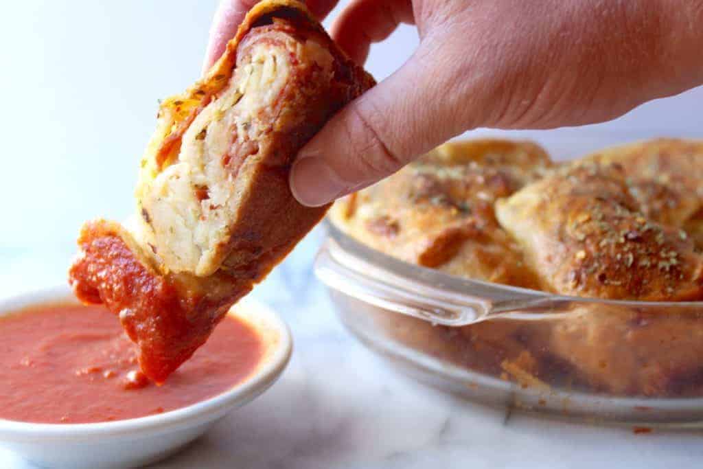 homemade pepperoni bread from scratch dipped into a bowl of pizza sauce