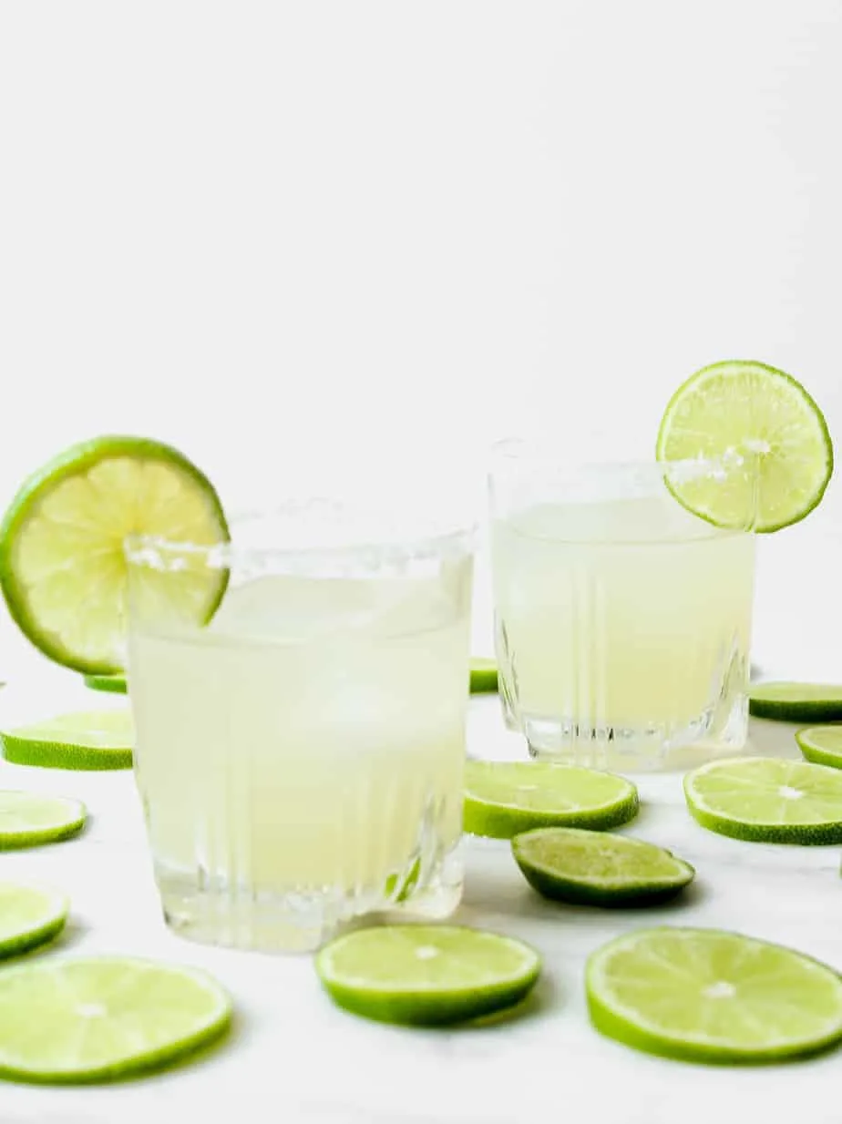two classic margaritas with lime wheels