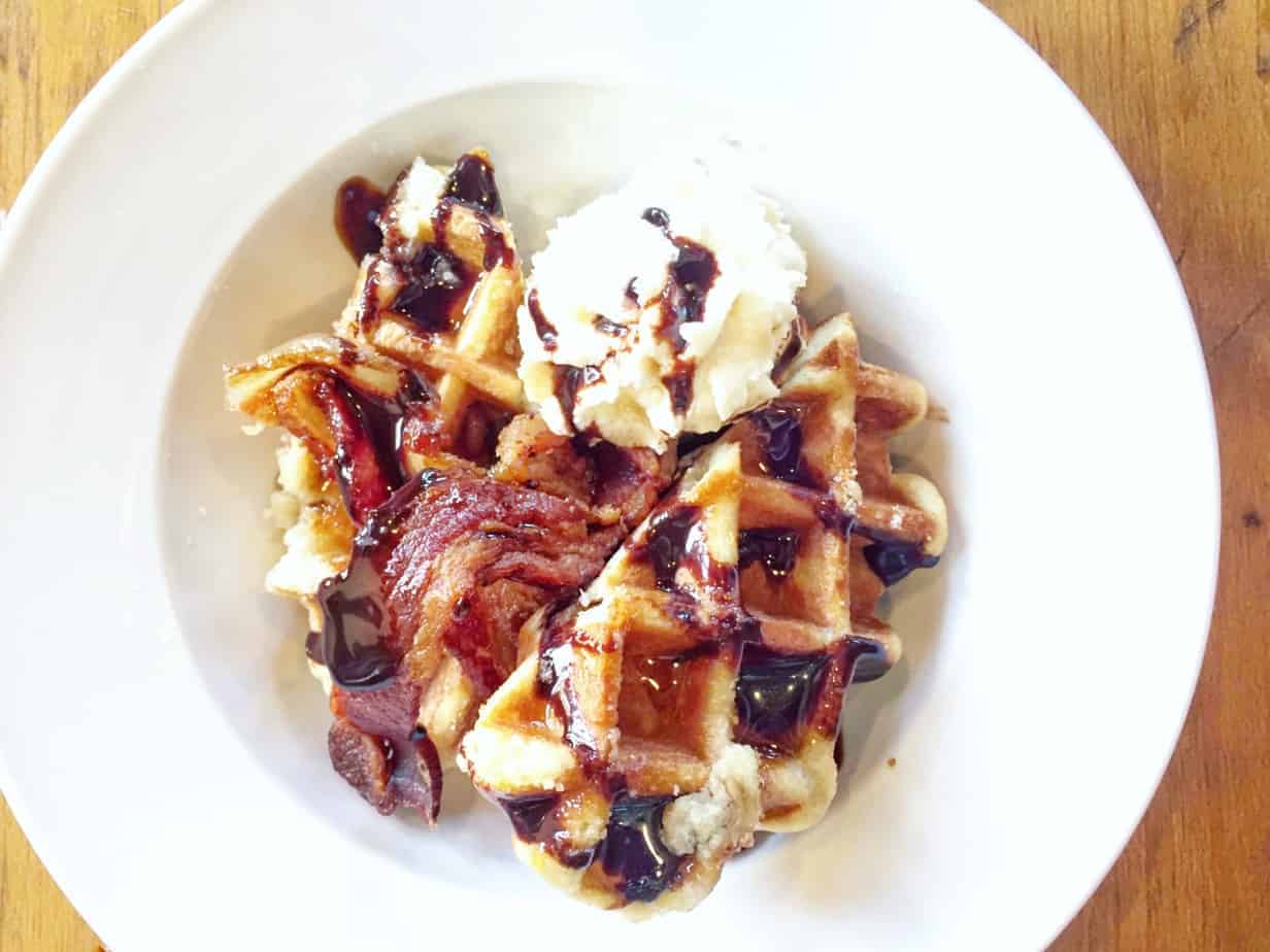 waffle with chocolate sauce and whipped cream in a white dish