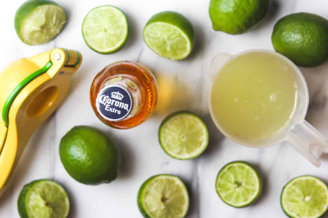 lime juice, limes and corona extra on a marble platter