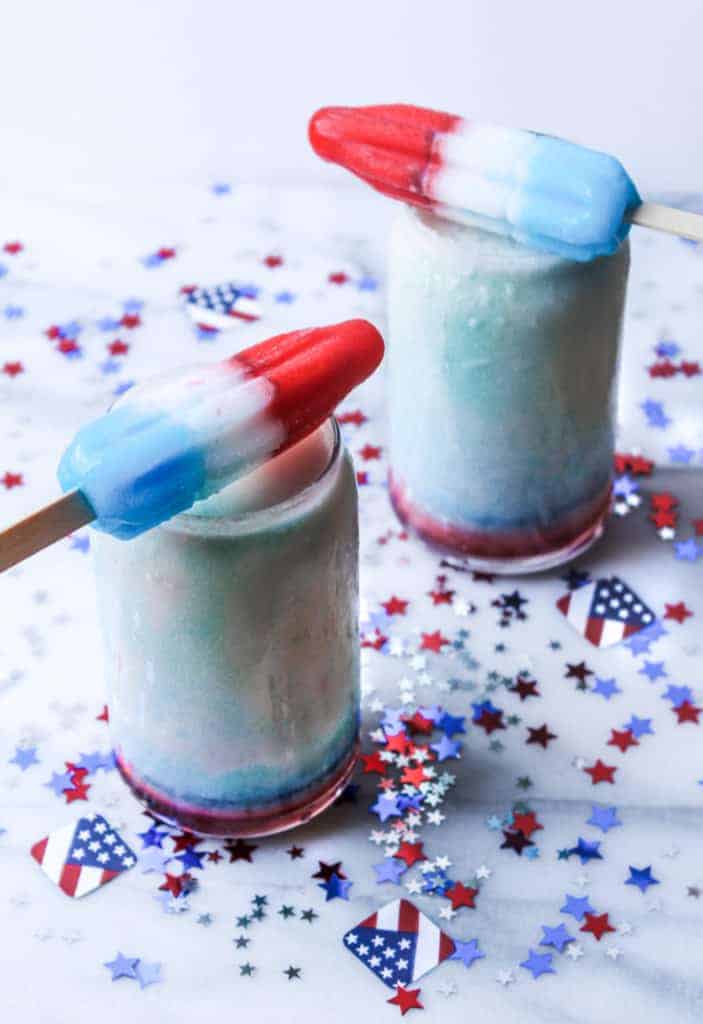 red white and blue popsicles balancing on top of two red white and blue drinks while melting