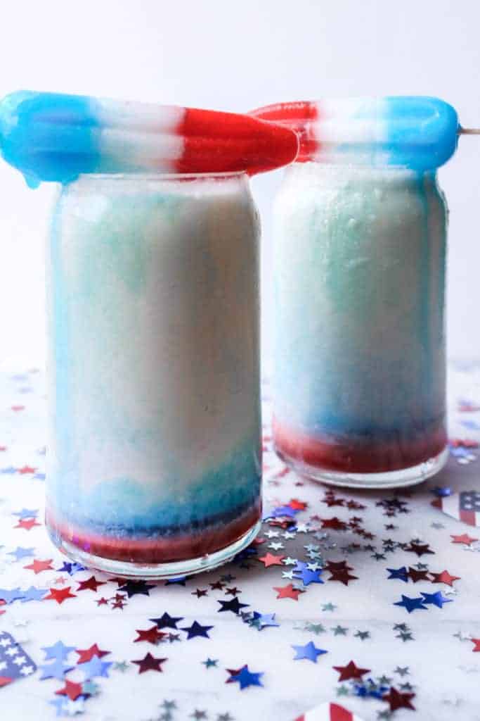 red white and blue popsicles balancing on top of two red white and blue drinks while melting