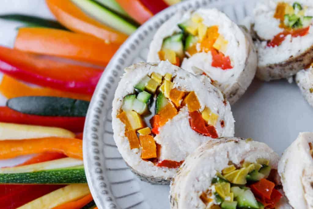 slices of chicken stuffed with bell peppers and zucchini on a white plate