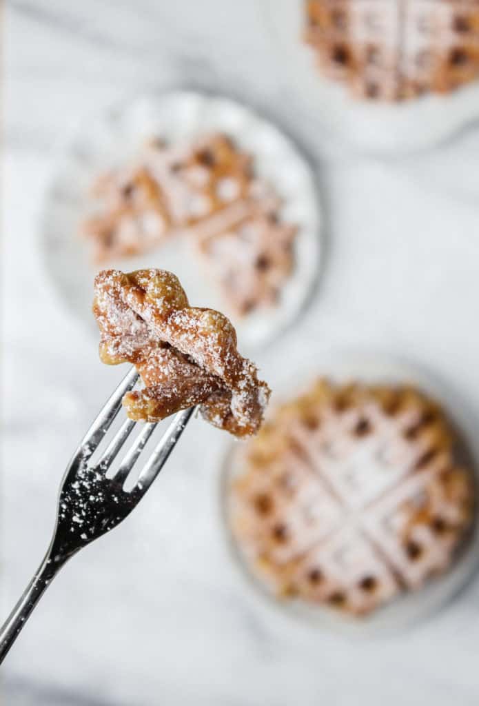 bite of pumpkin waffle on a silver fork with powdered sugar