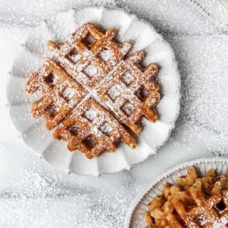 pumpkin waffles on plates with powdered sugar