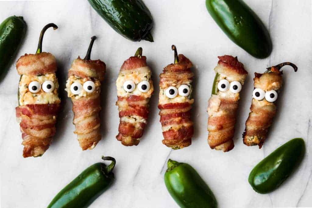 bacon wrapped jalapeno popper mummies in a line