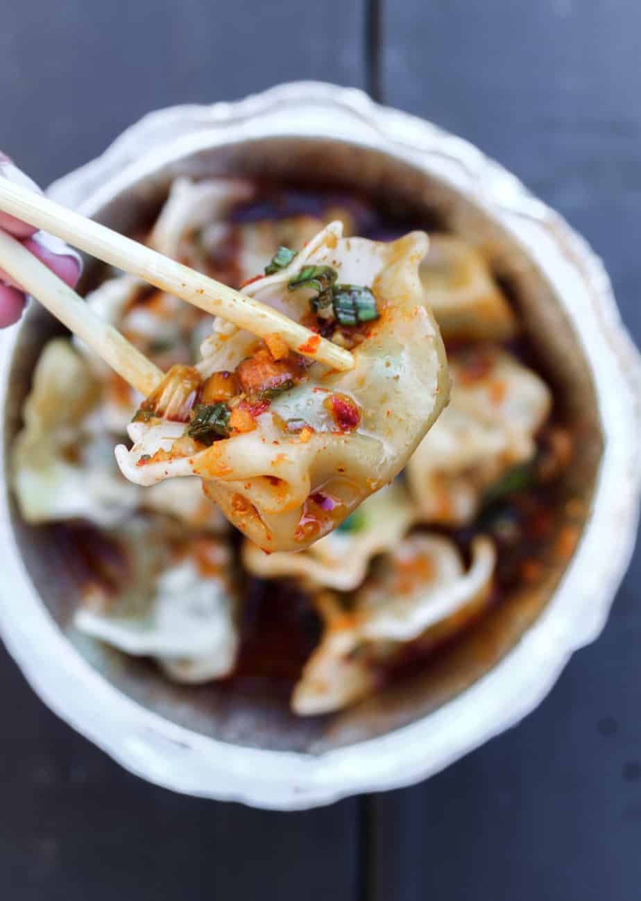 the dumpling lady eating a pork and chive dumpling with chopsticks