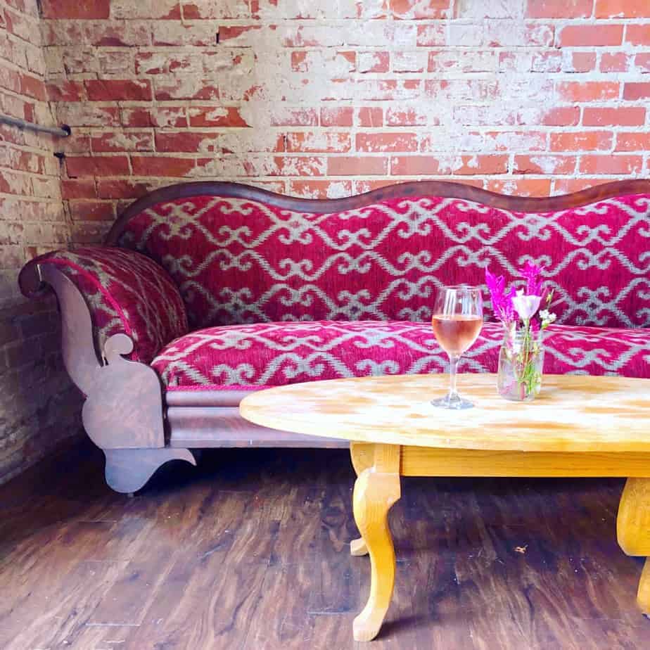 glass of rose wine on a coffee table with pink couch at lincoln's haberdashery