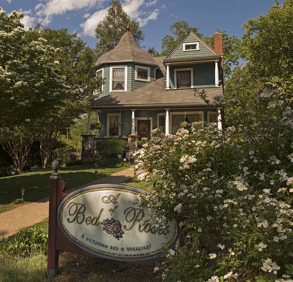 the front of a bed of roses bed and breakfast in asheville nc is painted green with rose bushes