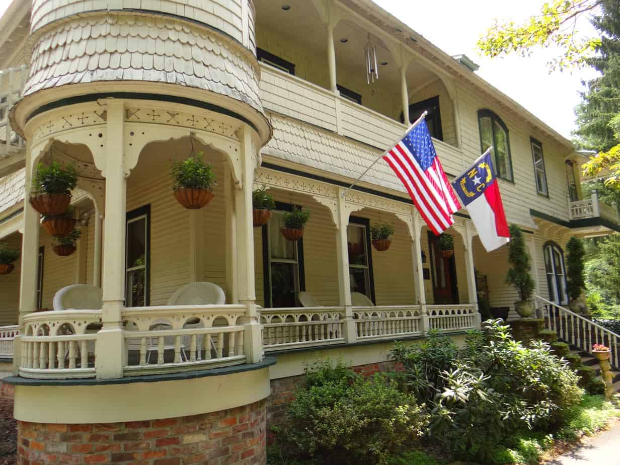 engadine inn and cabins white wrap around front porch with the united states flag and north carolina state flag