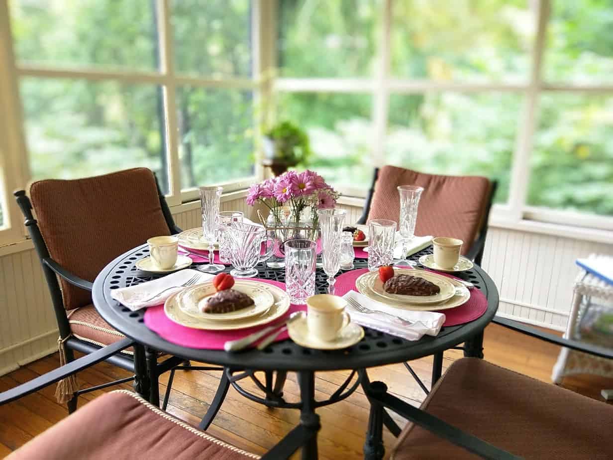 black table set with pink placemats for breakfast with fresh pink flowers at the pinecrest, an asheville bed and breakfast