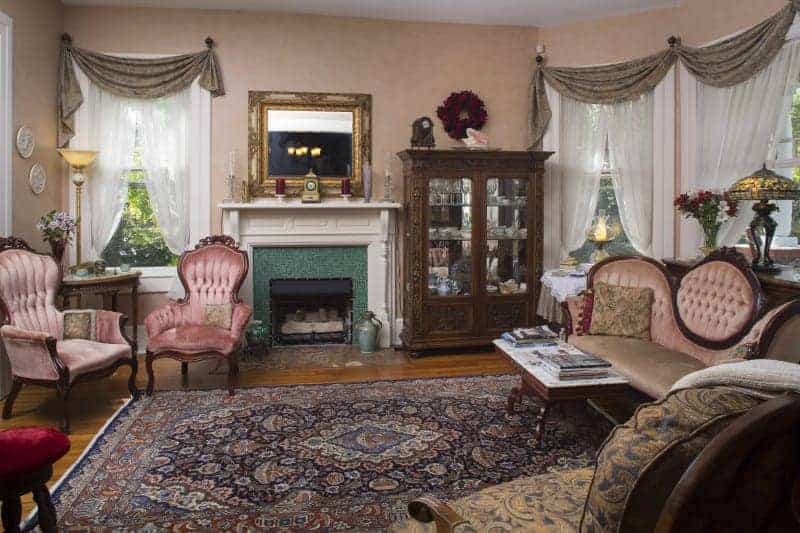 sitting room with pink chairs and a pink couch with purple rug and pink wallpaper and a green fireplace at a bed and breakfast near asheville