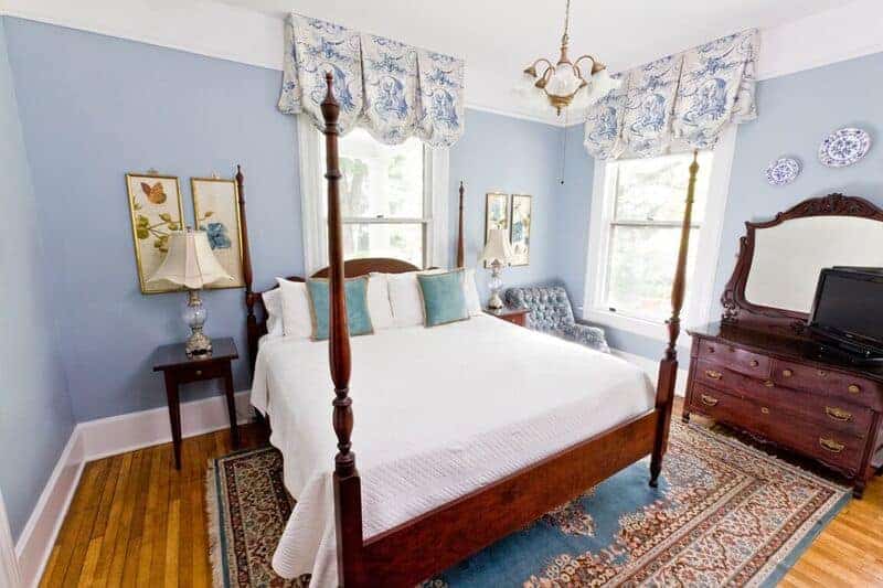 blue painted bedroom at an asheville bed and breakfast with wooden 4 post bed and wooden dresser