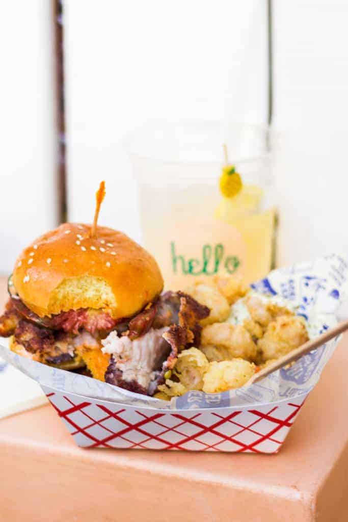 calabash fish sandwich at on a plate with french fries and shrimp on a pink table