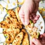 pulling apart crab stuffed baked jalapeno poppers to show cheese inside