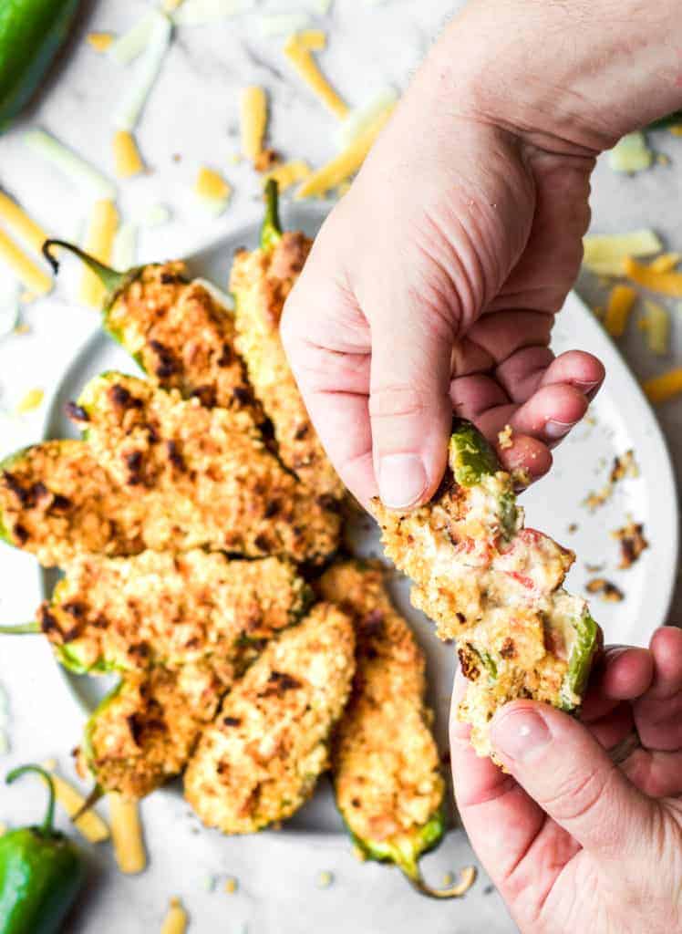 pulling apart crab stuffed baked jalapeno poppers to show cheese inside