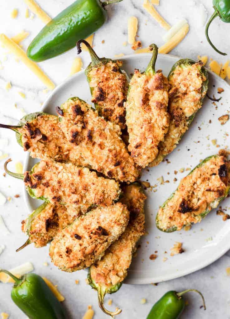 white platter of baked jalapeno poppers with jalapenos and shredded cheddar cheese