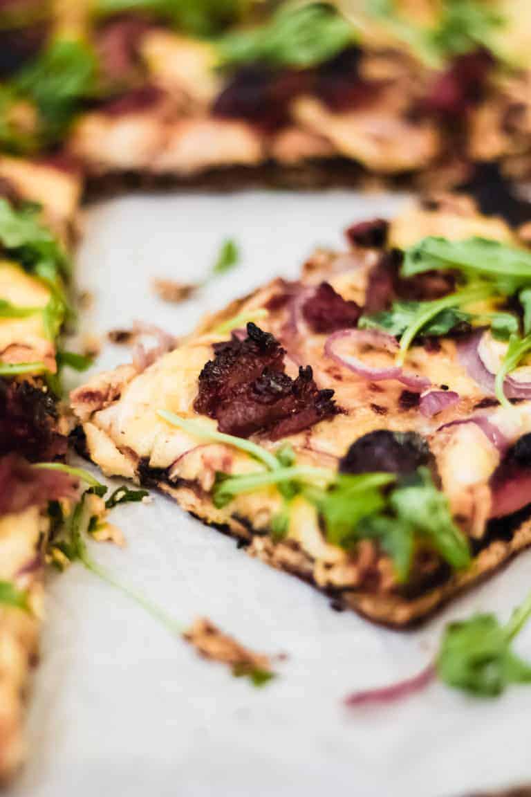 grilled bbq pizza on parchment paper with bbq ribs and red onion