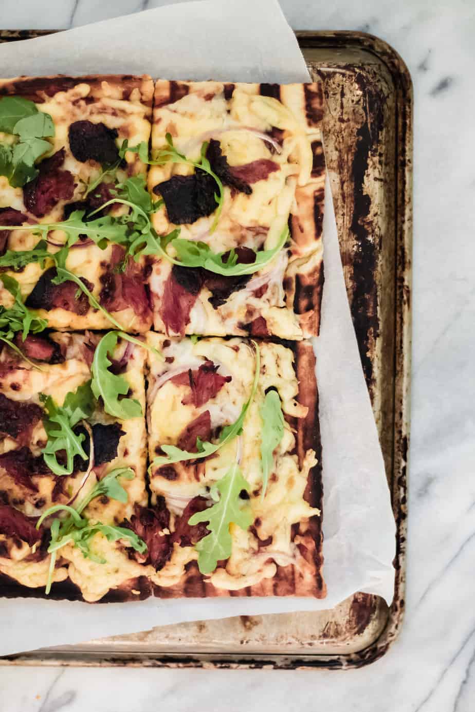 grilled bbq pizza on a sheet pan and marble surface