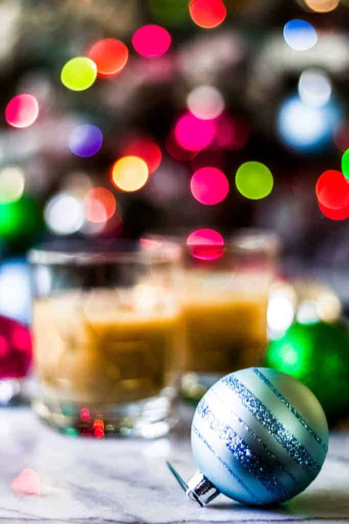 a blue christmas ornament with glitter with eggnog white russian cocktails in the background