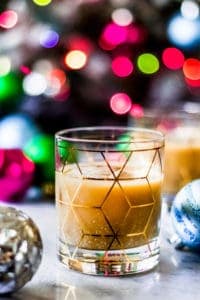 christmas white russian in a rocks cocktail glass with christmas ornaments in front of a christmas tree