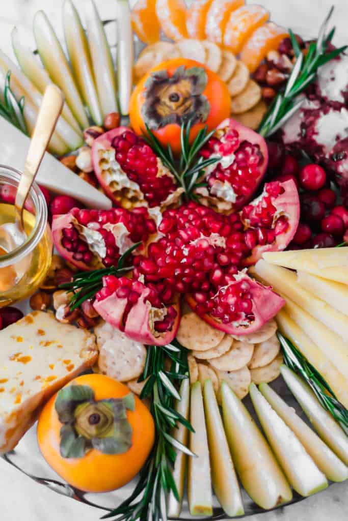 opening a pomegranate in the middle of a cheese platter