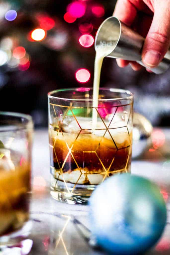 pouring eggnog into a christmas white russian cocktail