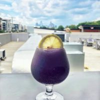 frozen purple hummingbird cocktail with the charlotte skyline in the background at the waterman