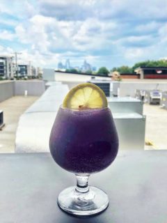 frozen purple hummingbird cocktail with the charlotte skyline in the background at the waterman