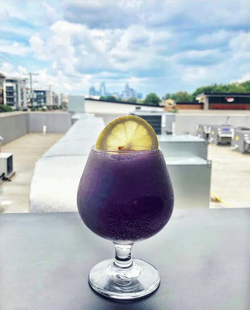 frozen purple hummingbird cocktail with the charlotte skyline in the background at the waterman