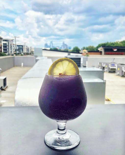 frozen purple hummingbird cocktail with the charlotte skyline in the background at the waterman 