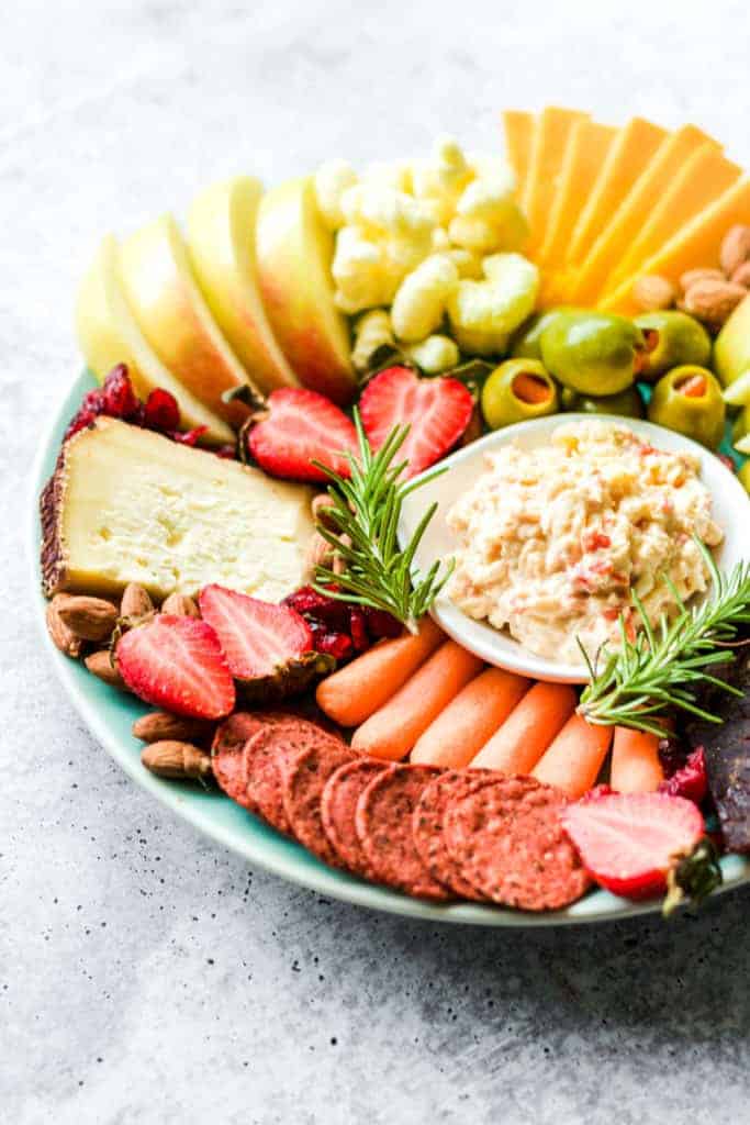 red crackers, pimento cheese, white cheese and strawberries on a teal plate