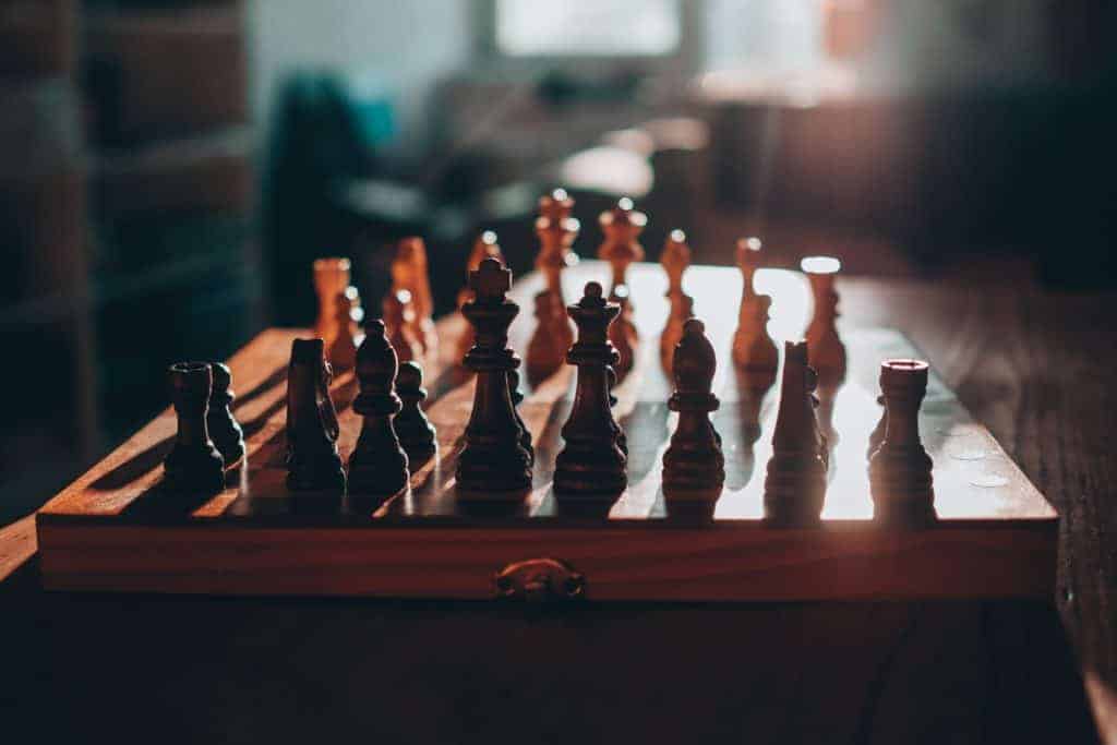 sun shining on a wooden chess set creating a shadow off of the pieces