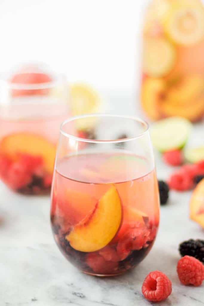 single wine glass of sangrial with fresh fruit on a marble background