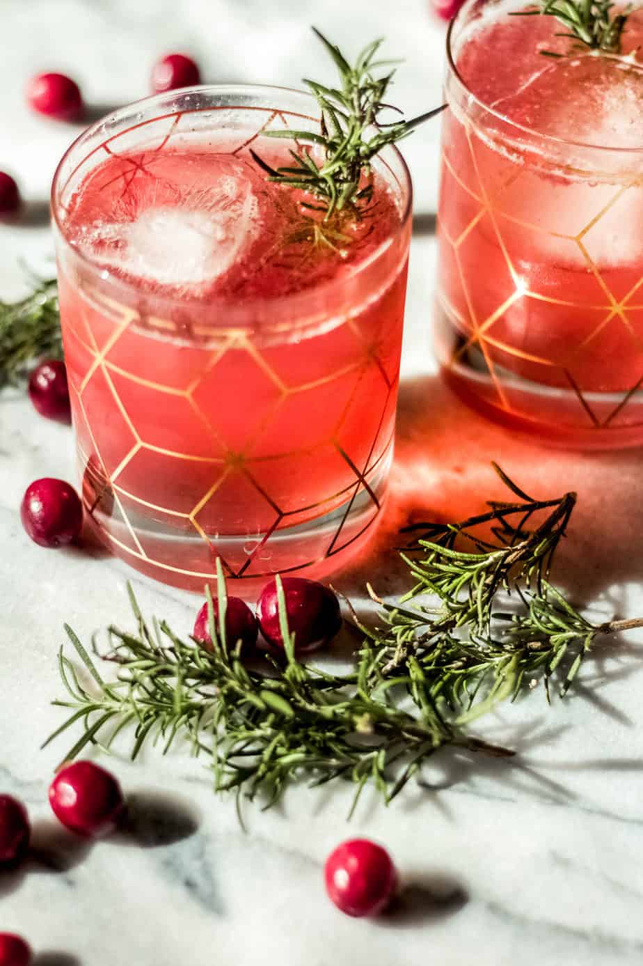 two cocktail glasses with gold design filled with pink colored cocktails