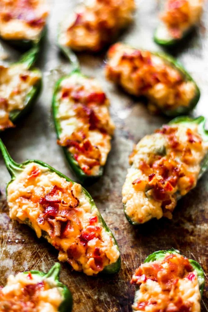 jalapeno pepper halves stuffed with pimento cheese and bacon on a metal sheet tray