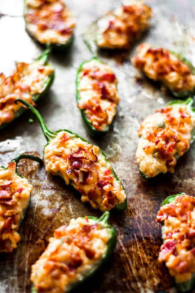 jalapenos stuffed with pimento cheese and bacon on a metal sheet tray