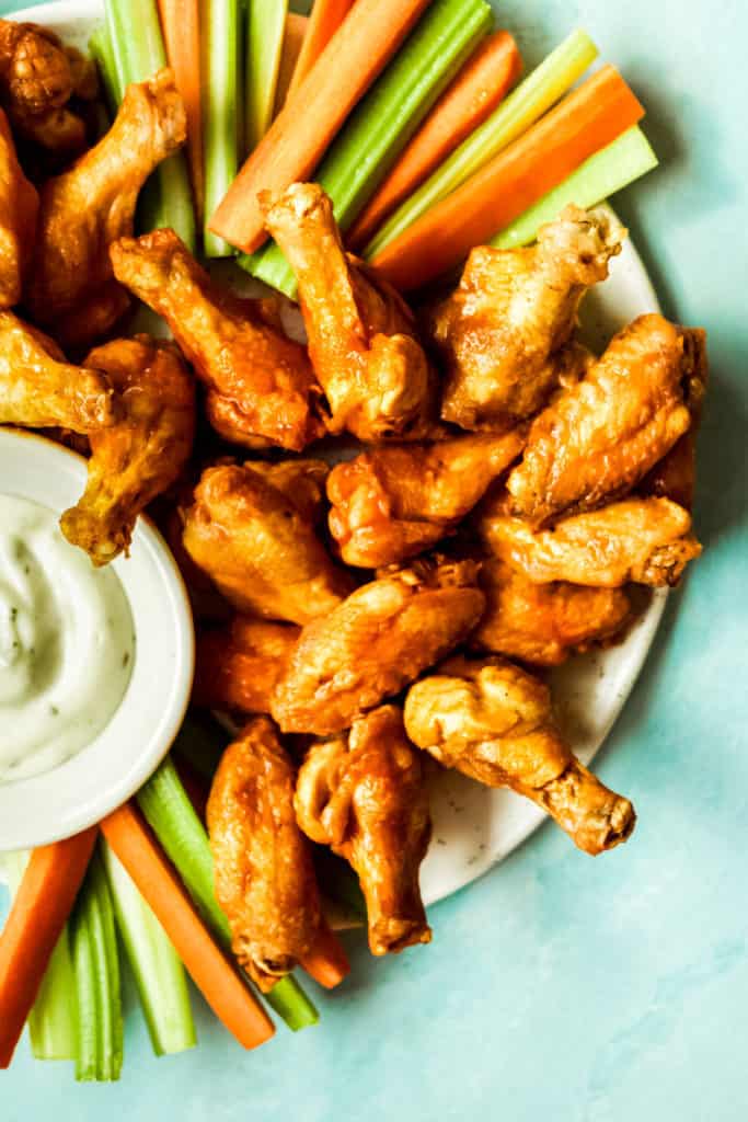 a plate of buffalo wings served with carrots celery and ranch