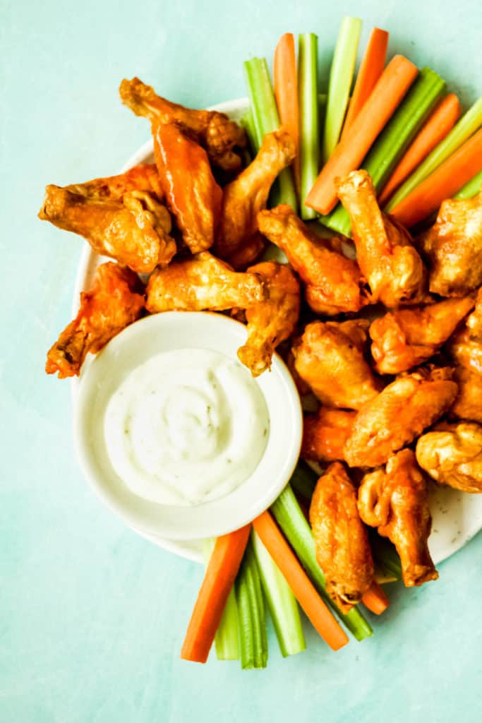 a plate of chicken wings with carrot and celery sticks and ranch sauce