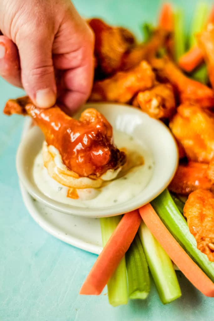 dipping a chicken wing into ranch sauce