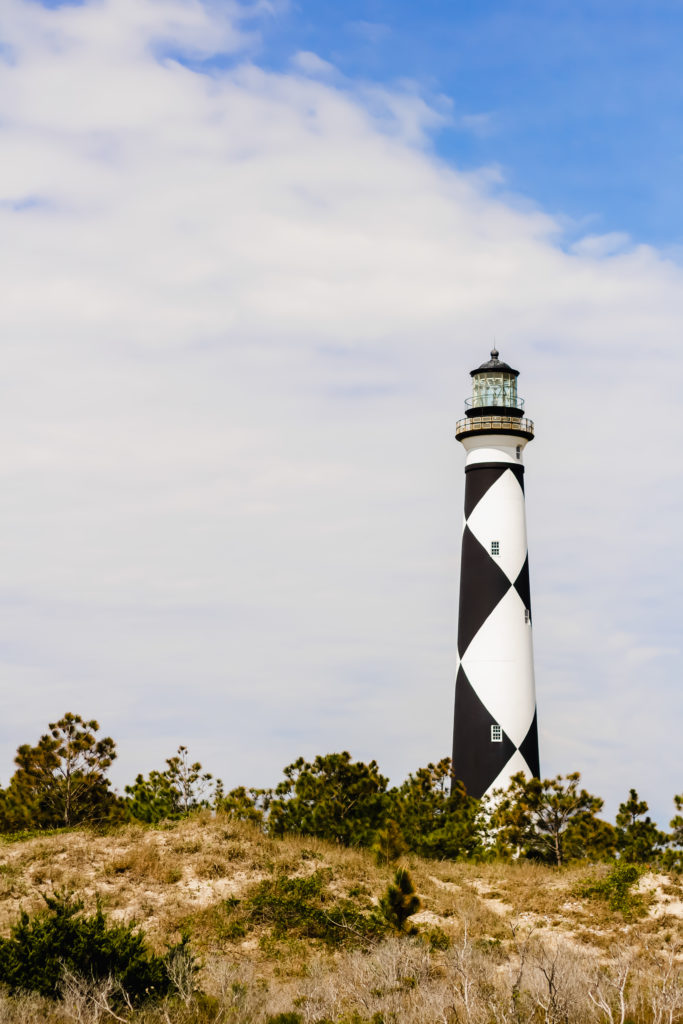 black and white diamond pattern cape lookout lighthouse against a blue sky