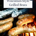 Four grilled, beer boiled brats and two foil-wrapped items sizzle on the grill. Text reads Wisconsin-Style Grilled Brats, So Easy! with offtheeatenpathblog.com at the bottom.