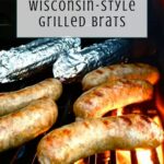 Four grilled beer boiled brats and two foil-wrapped items sizzle on a grill, with text above reading Beer-Boiled Wisconsin-Style Grilled Brats. The Off the Eaten Path logo is displayed at the bottom.